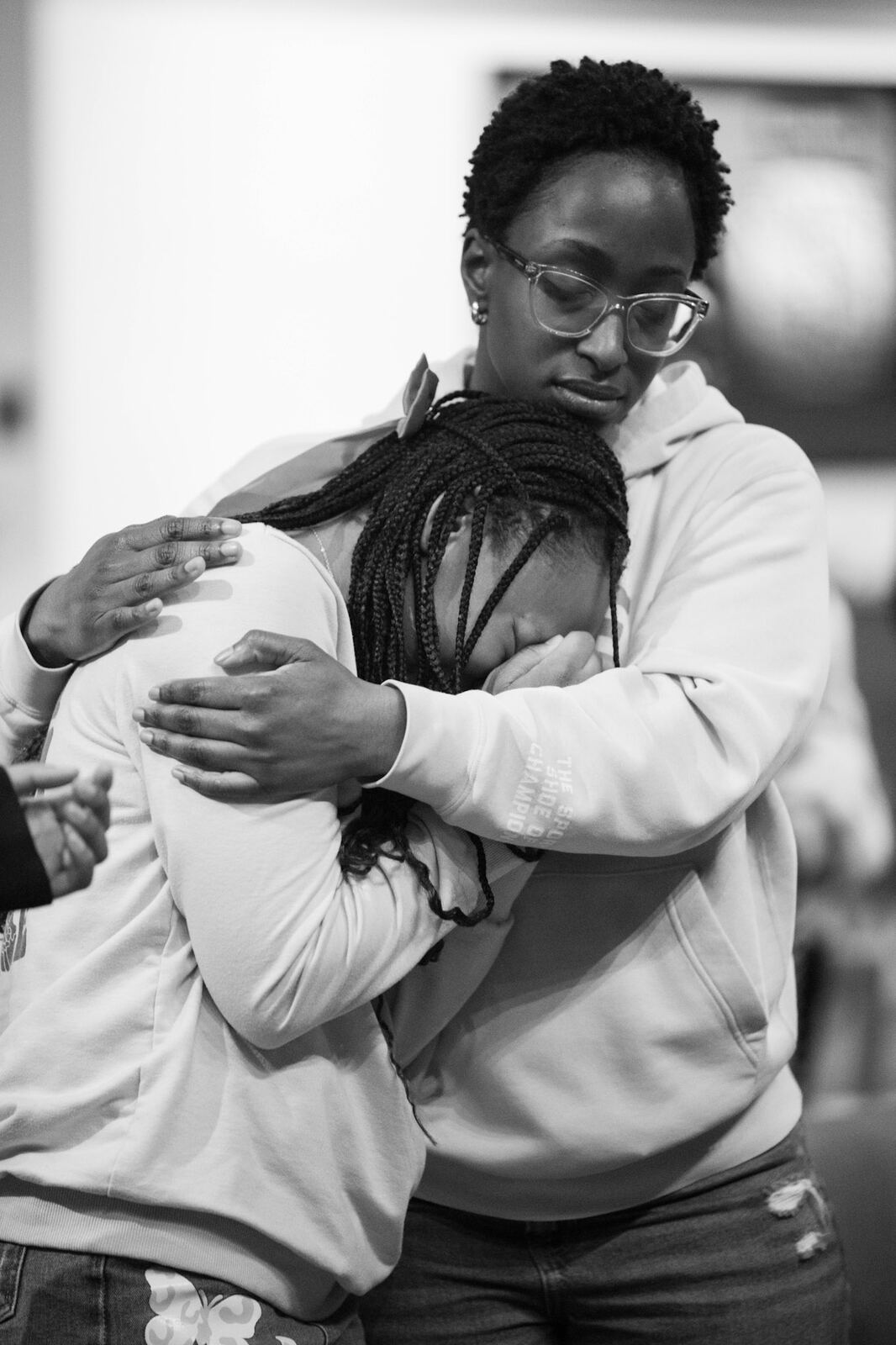Two young women embracing in prayer, in black and white
