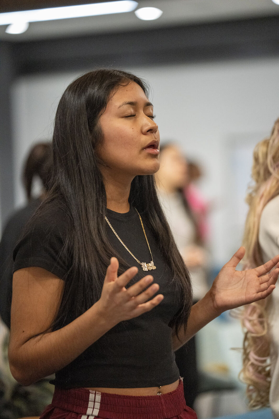 A young woman praying with open hands during worship